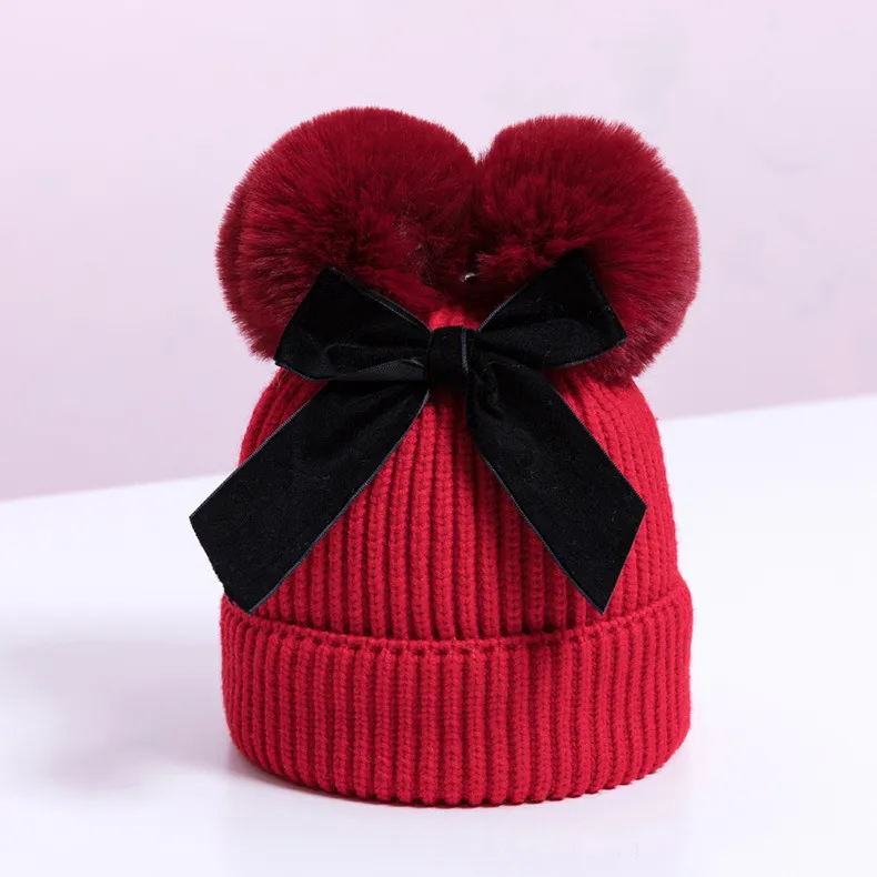 Knitted pompom hat with velvet bow