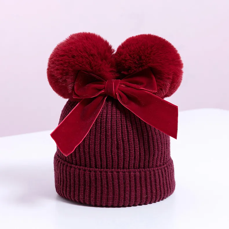 Knitted pompom hat with velvet bow