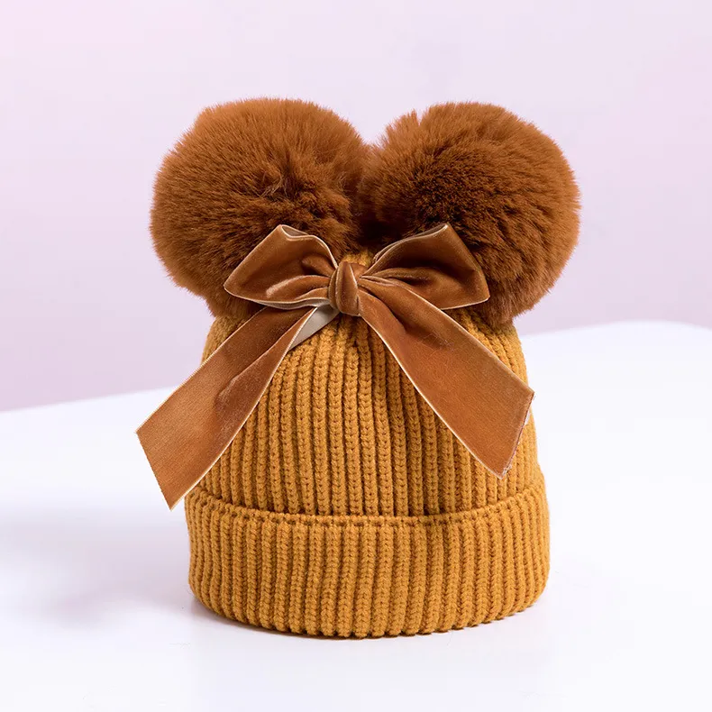 Knitted pompom hat with velvet bow